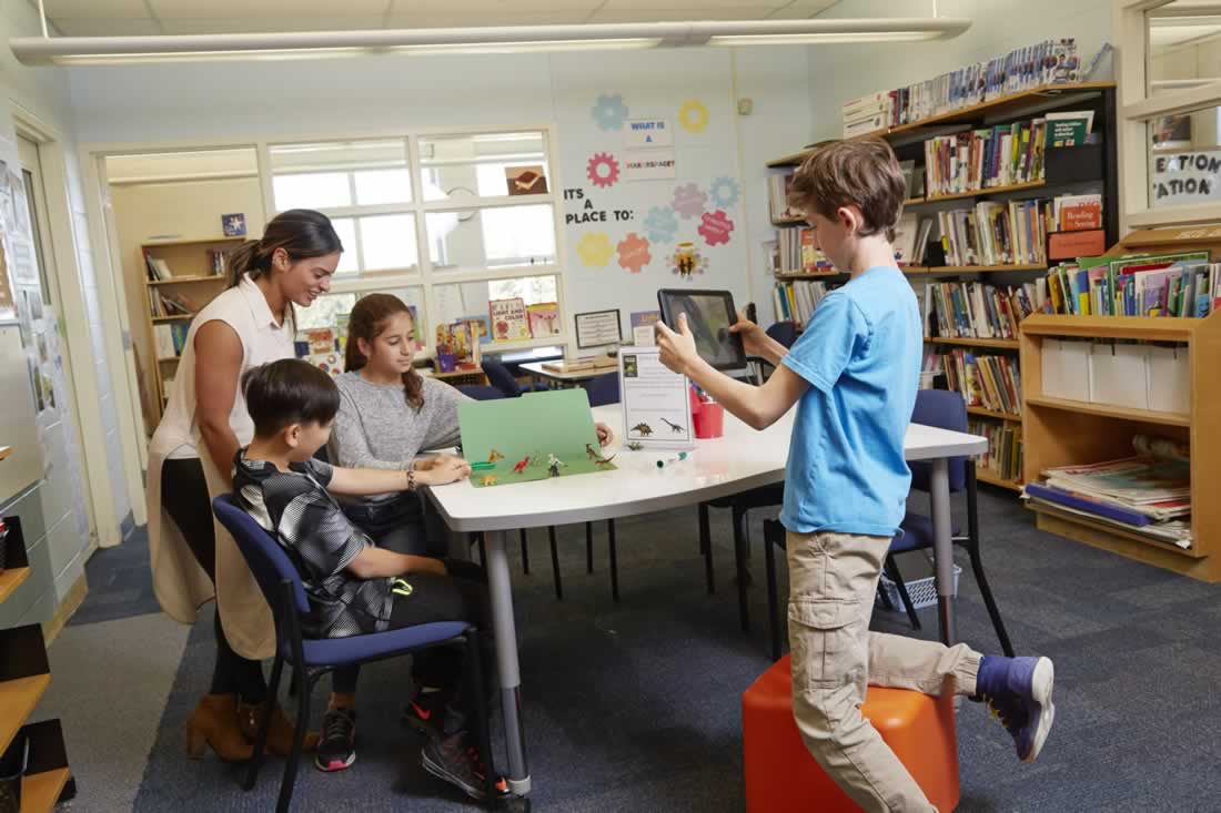 This is an image of a student taking pictures of a mini green screen with an ipad'.